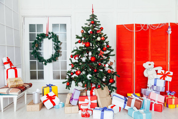 Árvore de Natal com presentes vermelhos Decoração de dezembro no interior da sala branca
 - Foto, Imagem