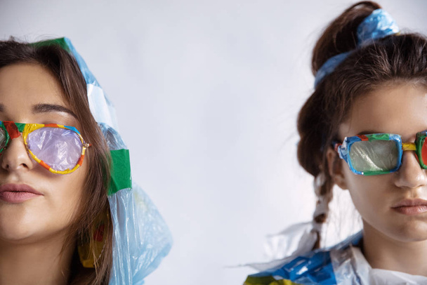 Women addicted of sales and clothes, wearing plastic, recycling concept - 写真・画像