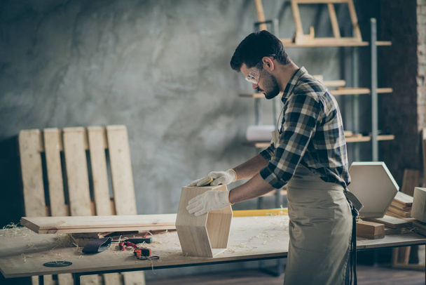 Profile side photo of focused man worker work with wooden shelf restore renew furniture polish surface in home garage - 写真・画像