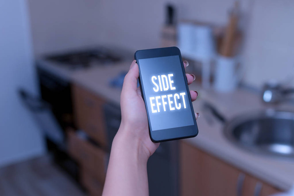 Conceptual hand writing showing Side Effect. Business photo text typically undesirable effect of a drug or medical treatment woman using smartphone and technological devices inside the home. - 写真・画像