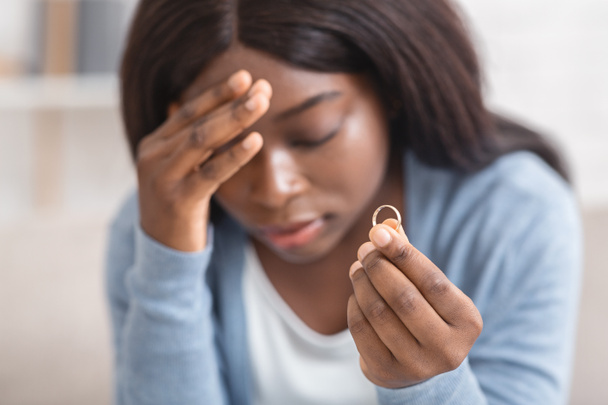 Menina negra perturbada segurando anel de casamento de ouro, deprimido sobre o divórcio
 - Foto, Imagem