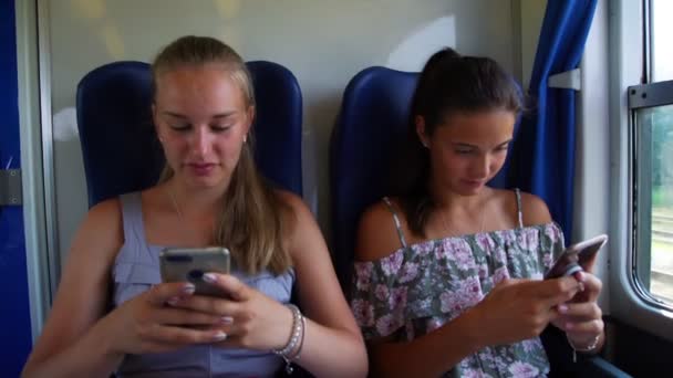 cute girl shows picture on phone to friend in train closeup - Кадры, видео