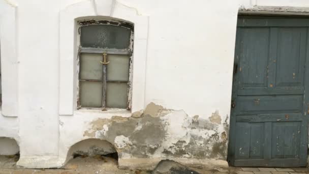 Weerbestendige en beschadigde muur van oud huis, gepleisterd wit met beschadigingen en scheuren. En houten oude deur. Close-up. - Video