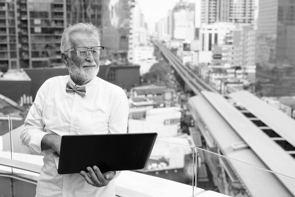 Красивый бородатый старший турист исследует город в черно-белом
 - Фото, изображение