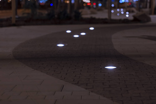 zachte focus nacht stad straat perspectief verharde weg oppervlak met lampen decoratie landschapsarchitectuur elementen licht - Foto, afbeelding