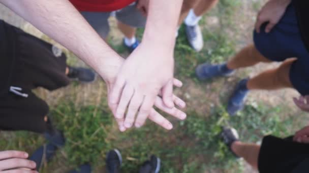 1つ1つを一つにまとめ若い選手のトップビューの手。親友のグループは円の中心に腕を置き、それらを上げる。友情とチームワークの概念。スローモ - 映像、動画