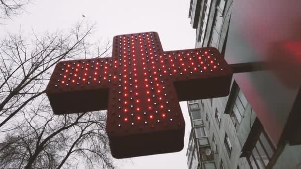 ビルのファサードビューの薬局の看板、赤い十字薬局の看板やシンボルは、曇った空に対して通りから。 - 映像、動画