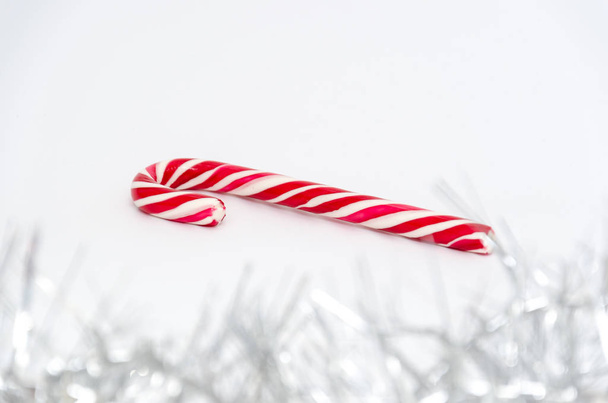 Clásico caña de caramelo de Navidad brillante rojo y blanco sobre fondo blanco. Guirnalda en primer plano. Enfoque selectivo. Fondo navideño festivo. Copiar espacio
 - Foto, Imagen