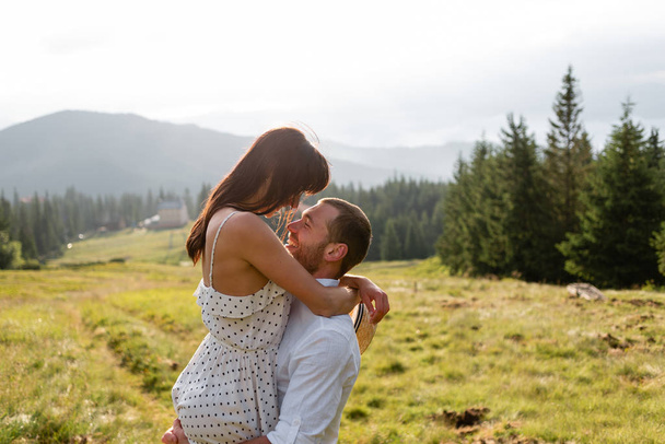 A man holds a woman in his arms in the middle of a field - Foto, afbeelding