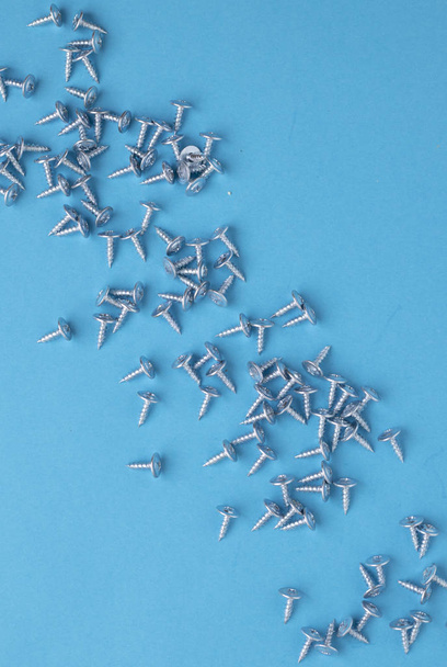 Many screws on blue paper, blurred background - Photo, Image