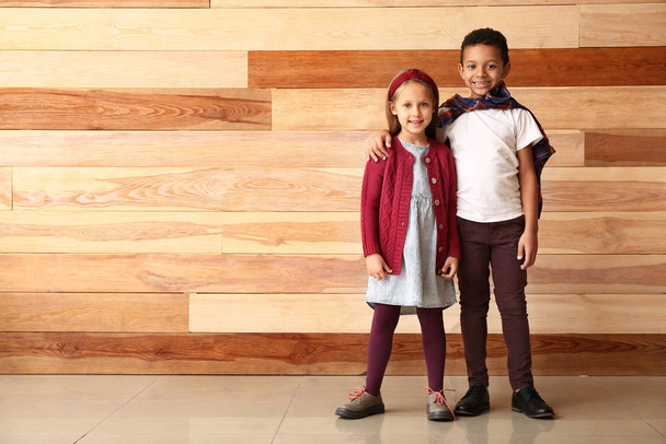 Fashionable little children in autumn clothes near wooden wall - Фото, зображення