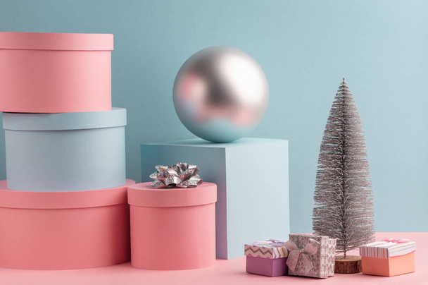 Fir tree, ball, round and square gift boxes on pink and teal background - Photo, image