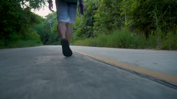 Matala kulma seuraa laukaus turisti Flip Flops kävely keskellä tietä viidakossa
 - Materiaali, video
