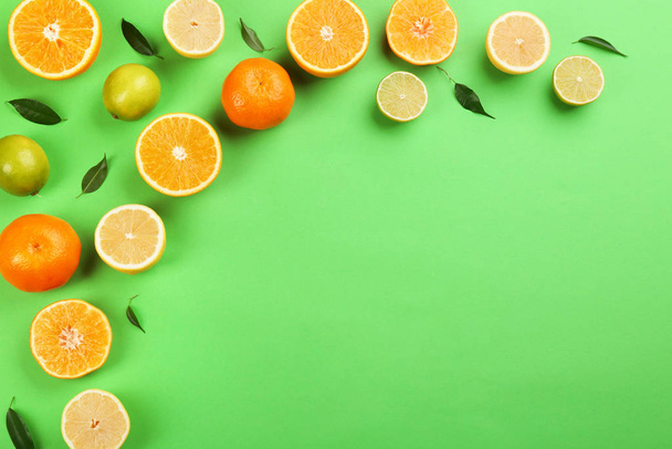 Flat lay composition with tangerines and different citrus fruits on green background. Space for text - 写真・画像
