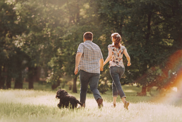 couple running in the park with their dog in summer - 写真・画像