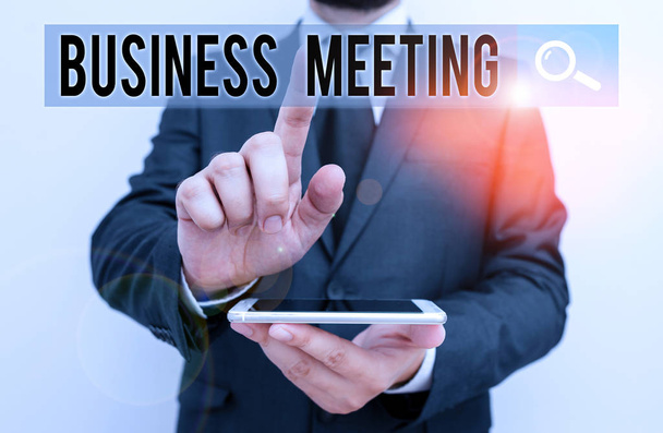 Writing note showing Business Meeting. Business photo showcasing gathering of two or more showing to discuss business ideas Male human wear formal work suit hold smartphone using hand. - Photo, Image
