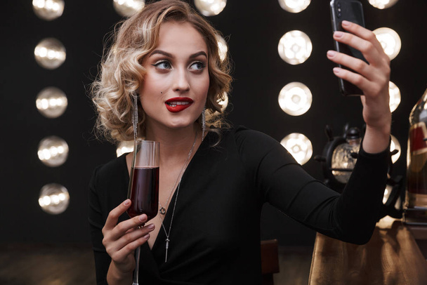 Image of attractive blonde woman using cellphone and drinking re - Fotografie, Obrázek