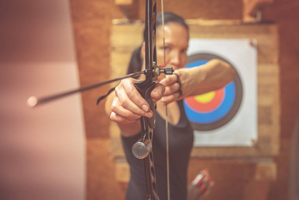 Young beautiful woman in sports competitions, archery, aiming at the target - Photo, Image