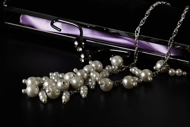 Pearl beads with a velvet black clutch on the table. - Photo, Image