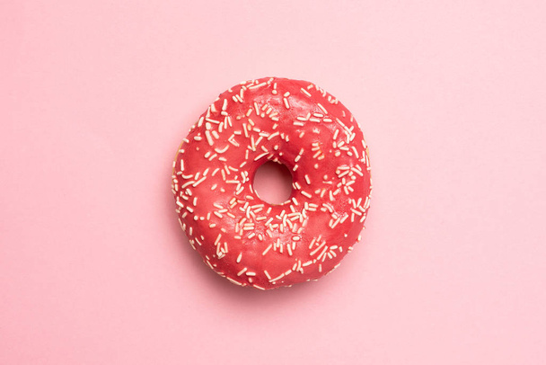 Sweet pink donut with white sprinkles on a pink background flat lay - Foto, Imagen