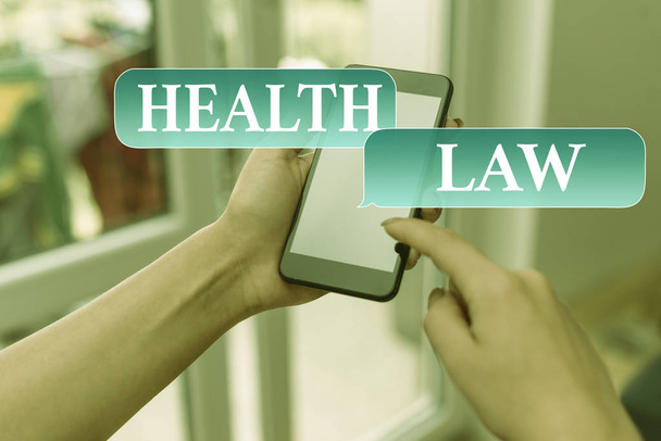 Text sign showing Health Law. Conceptual photo law to provide legal guidelines for the provision of healthcare woman using smartphone office supplies technological devices inside home. - Photo, Image