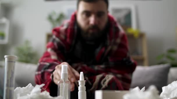 Ill man uses nasal spray on sofa in living room - Materiał filmowy, wideo