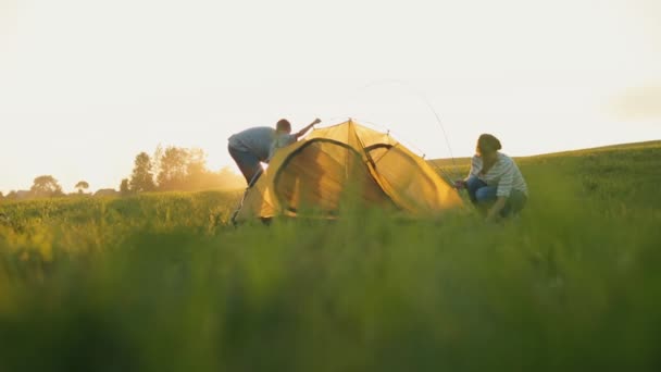 Happy family putting up a tent together In field. Children help their parents - 映像、動画