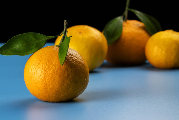 Yellow and ripe tangerines on a blue background. - Valokuva, kuva