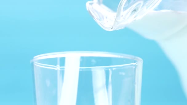 milk is poured into a glass on blue background - Video