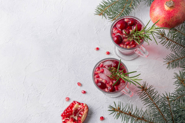 Granaatappel kerstcocktail met rozemarijn, cranberry, champagne, club soda op grijze betonnen tafel. Kerstdrank. - Foto, afbeelding