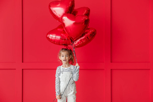 Cute little girl with air balloons on color background. Valentines Day celebration - Foto, afbeelding
