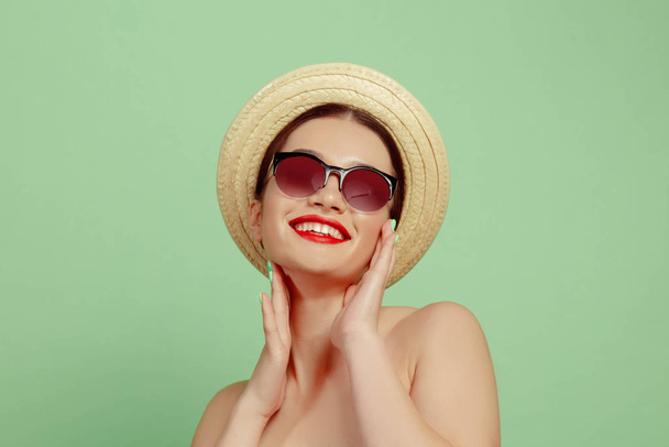 Porträt einer schönen jungen Frau mit hellem Make-up isoliert auf grünem Studiohintergrund - Foto, Bild
