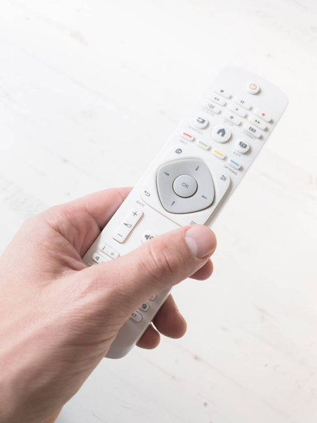 Hand holding TV remote controller on a white background. - Photo, Image