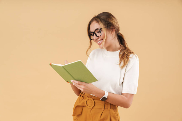Image of attractive woman smiling and writing down notes in diary book - Photo, Image