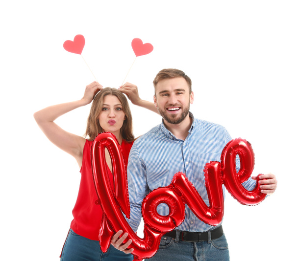 Happy young couple with balloon in shape of word LOVE on white background. Valentine's Day celebration - Photo, Image