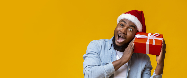 Смешной черный человек, держащий рождественскую подарочную коробку, чудо-белые внутри
 - Фото, изображение