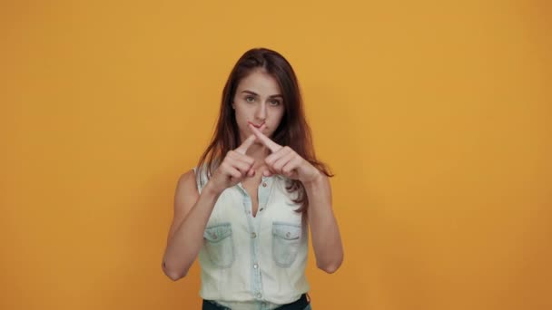 Young woman in blue denim shirt keeping hands crossed, looking directly - Séquence, vidéo