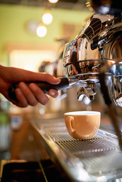 Female barista is making a coffee with a coffee machine  - Фото, изображение