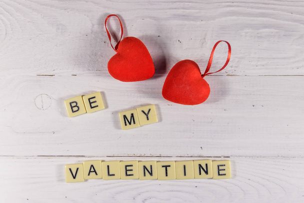 Corazones rojos y texto "Sé mi San Valentín" sobre fondo blanco de madera
 - Foto, imagen