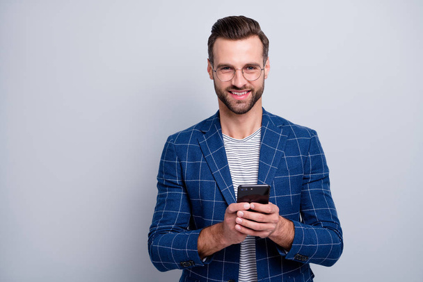 Photo of cheerful positive handsome man smiling toothily browsing through telephone having free time fun during business conference isolated grey background - Valokuva, kuva