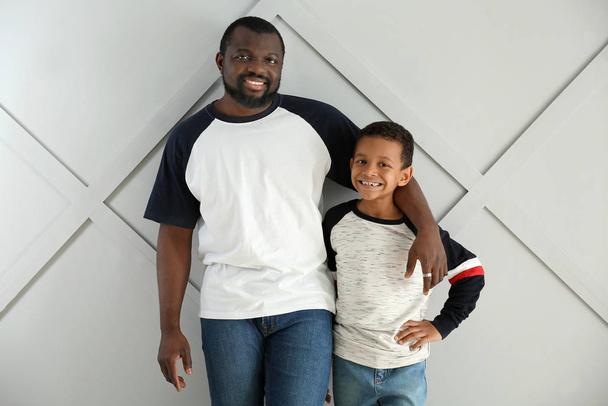 Porträt eines afrikanisch-amerikanischen Mannes mit seinem kleinen Sohn auf hellem Hintergrund - Foto, Bild