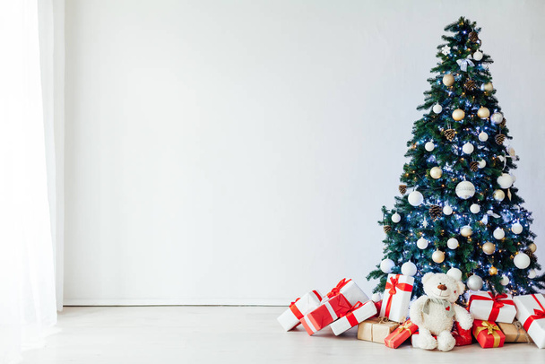 Árbol de Navidad con regalos de decoración de diciembre en el interior de la habitación blanca como fondo
 - Foto, Imagen