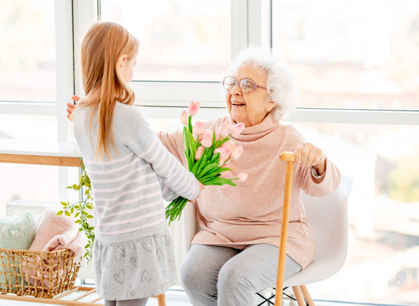 Girl presenting bouquet to old woman - Foto, imagen