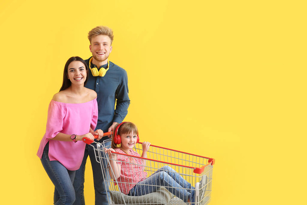 Family with shopping cart on color background - Фото, зображення