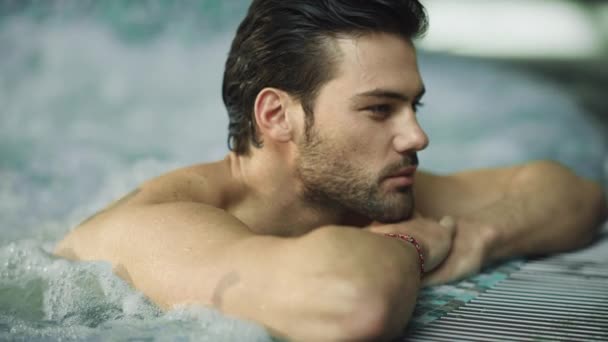 Portret seksownego mężczyzny w wannie z hydromasażem. Przystojny facet relaksuje się w basenie - Materiał filmowy, wideo
