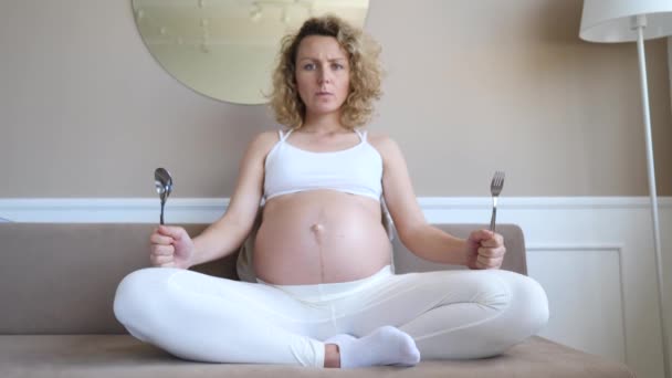 Hungry Dissatisfied Pregnant Woman Holding Spoon And Fork In Hands Waiting For Food. - Materiał filmowy, wideo