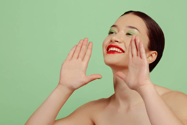 Портрет красивої молодої жінки з яскравим макіяжем ізольовано на зеленому студійному фоні
 - Фото, зображення