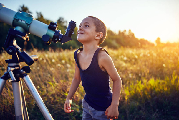 Kleiner Junge mit Teleskop in der Natur, um das Universum zu erkunden. - Foto, Bild