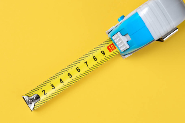 Measuring tape isolated over yellow bakground. Carpenter and Construct concept. - Фото, зображення