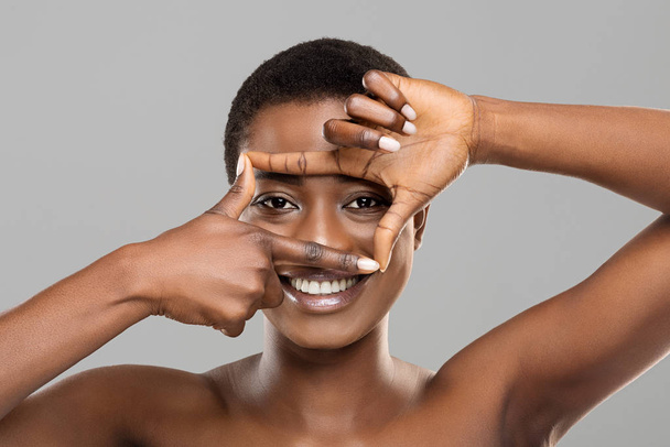 Attraente afro donna incorniciando i suoi bellissimi occhi con le dita
 - Foto, immagini